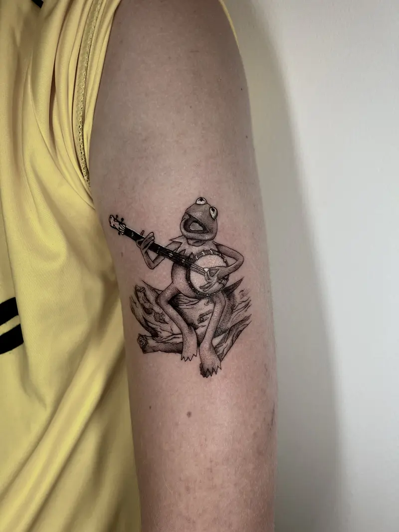 Rana tocando la guitarra sentada sobre hojas, blackwork.