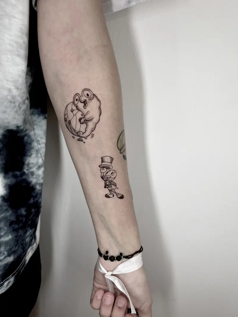 Dos tatuajes cartoon: rana con gafas y grillo con sombrero, blackwork.